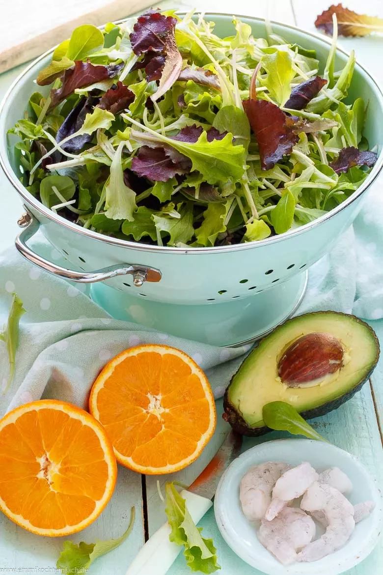 Zutaten für den gesunden Salat sind Avocado, Orangen und Garnelen sowie Pflücksalat